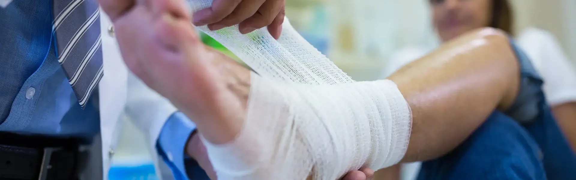 male-doctor-bandaging-foot-female-patient 1